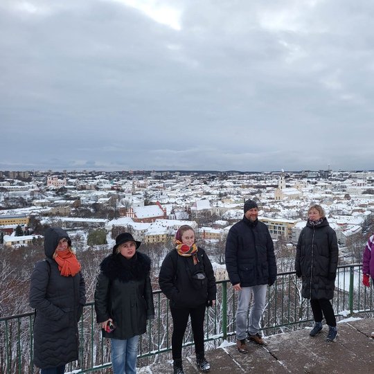 Ekskursijos dalyviai pozuoja nuotraukai ant Trijų Kryžių kalvos. Už nugaros Vilniaus panorama su apsnigusiais stogais.