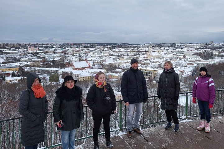 Ekskursijos dalyviai pozuoja nuotraukai ant Trijų Kryžių kalvos. Už nugaros Vilniaus panorama su apsnigusiais stogais.