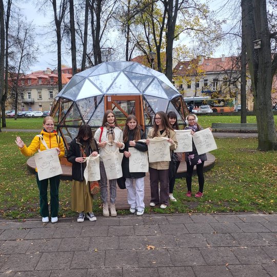 Istorijos būrelio nariai pozuoja nuotraukai su Vilniaus pilių maišeliais priešais Vilniaus pilių kupolą.