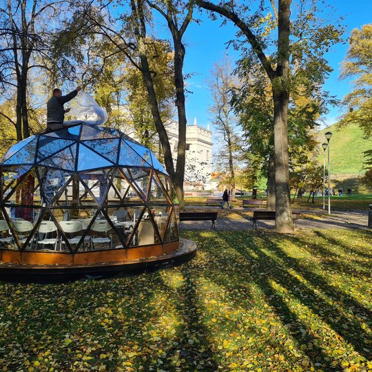 Vilniaus pilių kupolas iš lauko, nuo dar kito kampo. Iš vidaus, pro stogo langą matosi išlindęs darbininkas dedantis brezentą ant stogo.
