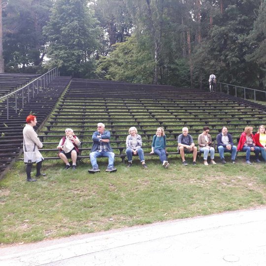 Ekskursijos dalyviai, susėdę Dainų slėnio estradoje.