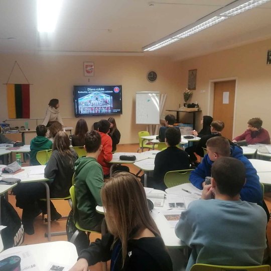 Fotografuota aštuntokų klasė iš mokinių nugarų.