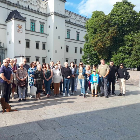 Gausi ekskursijos grupė vakarėjant įsiamžino prie Valdovų rūmų.