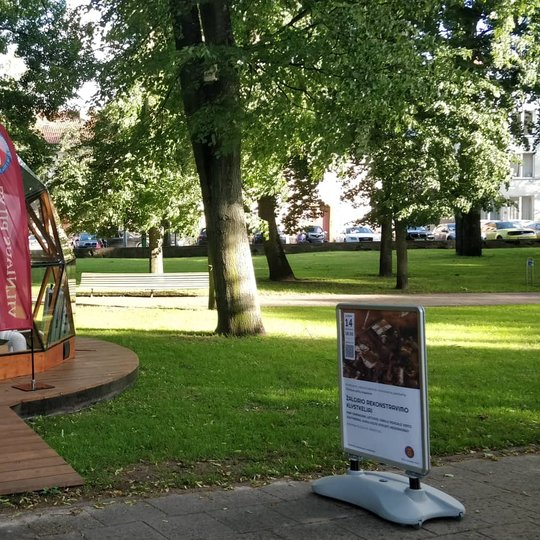 Vilniaus pilių kupolas iš lauko. Šalia kupolo stovintis vyriškis pro duris klausosi paskaitos.  