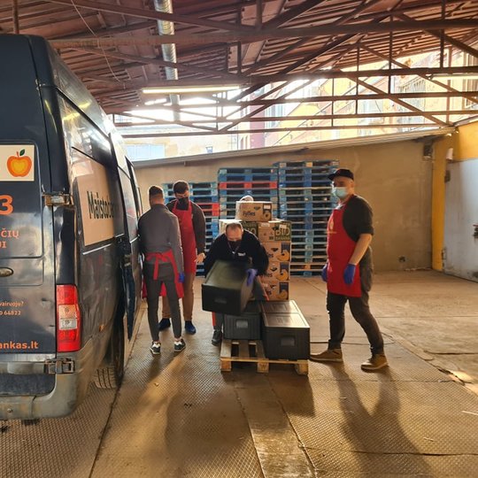 Maisto banko savanoriai krauna produktus į autobusiuką.