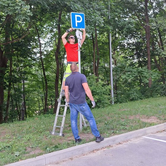Tiesinamas nurodomasis kelio ženklas, rodantis neįgaliųjų stovėjimo vietas.