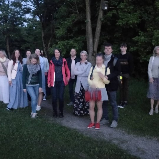 Renginio dalyviai šalia medžių, ant stalo kalno.