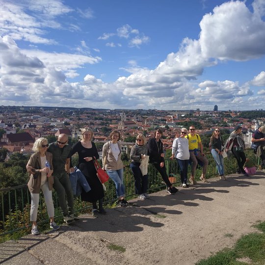 Ekskursijos dalyviai priešais Trijų Kryžių paminklą. Jiems  už nugaros matosi Viliaus panorama su Gedimino kalnu. 