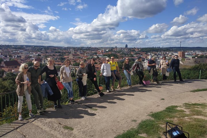 Ekskursijos dalyviai priešais Trijų Kryžių paminklą. Jiems už nugaros matosi Viliaus panorama su Gedimino kalnu.