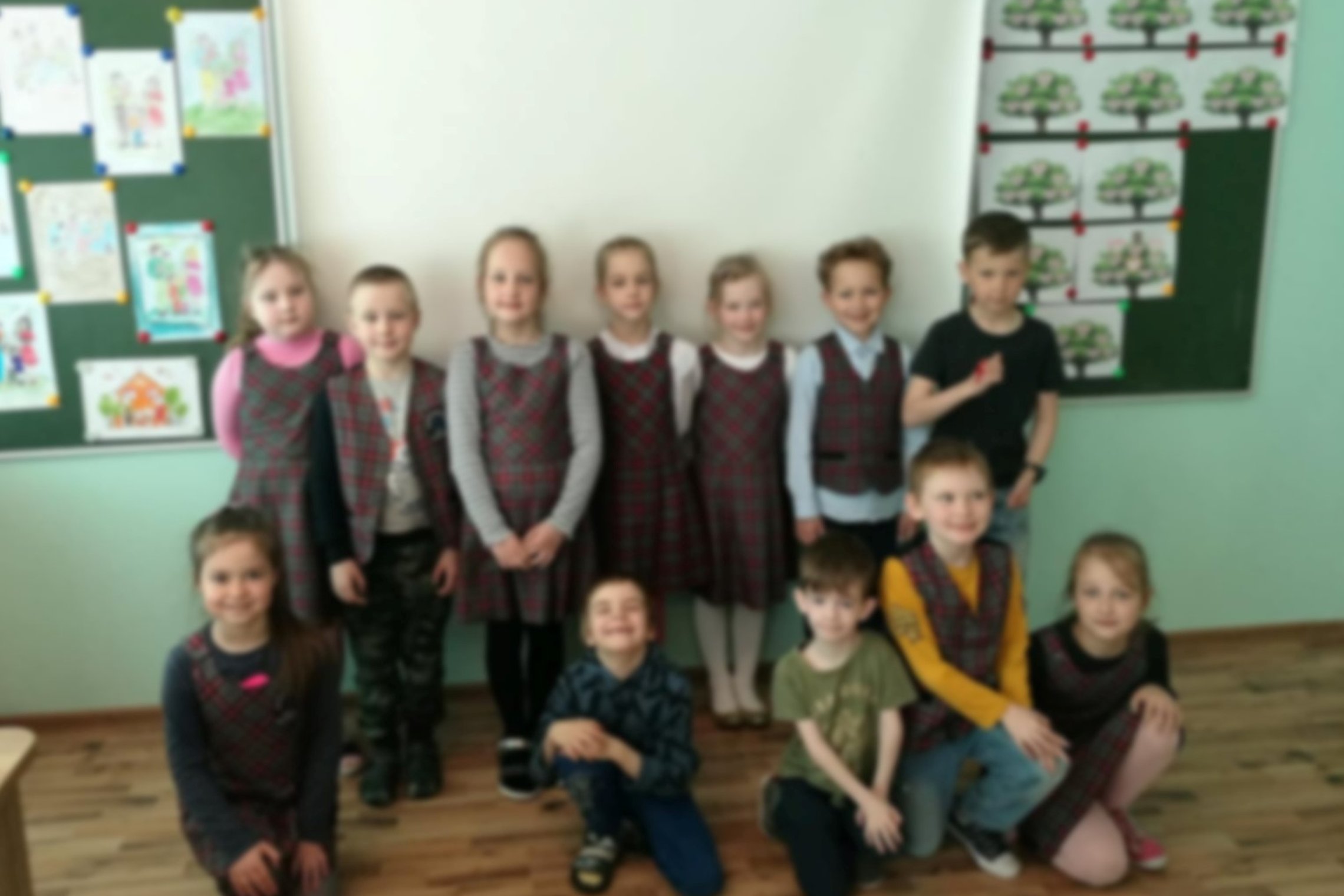 Vaikai pozuoja nuotraukai klasėje.