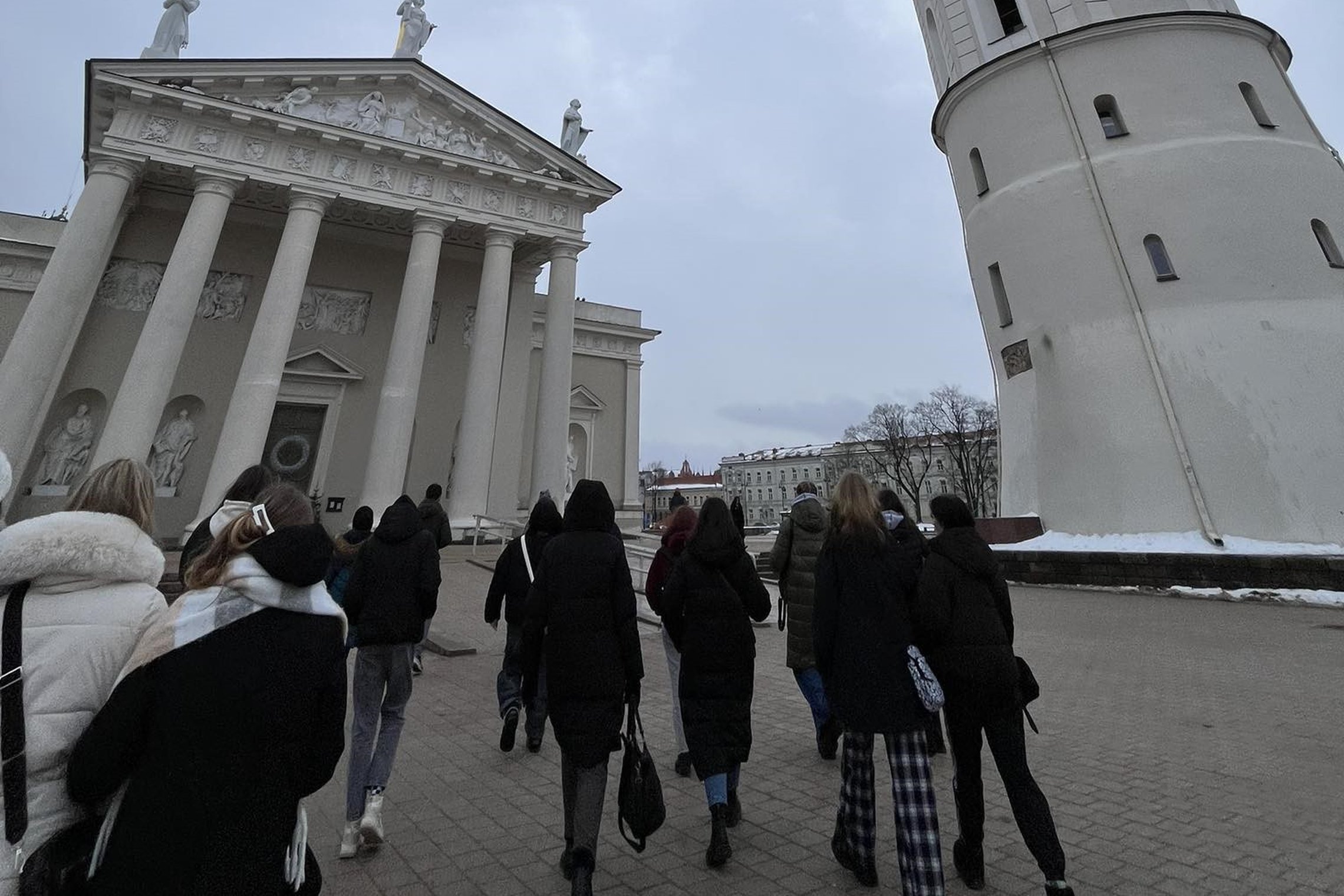 Nuotraukoje grupė žmonių, einančių Katedros ir varpinės link.