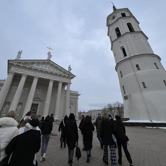 Nuotraukoje grupė žmonių, einančių Katedros ir varpinės link.