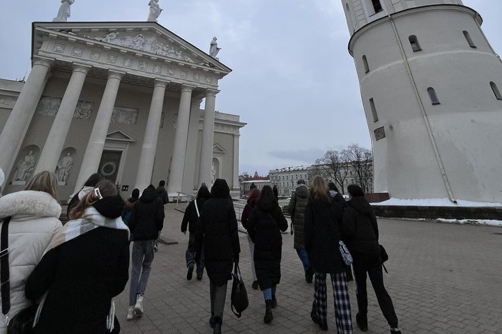 Nuotraukoje grupė žmonių, einančių Katedros ir varpinės link.