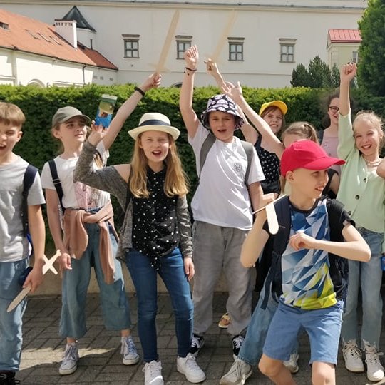 Vaikai iškelia medinius kalavijus Nacionalinio muziejaus kiemelyje.