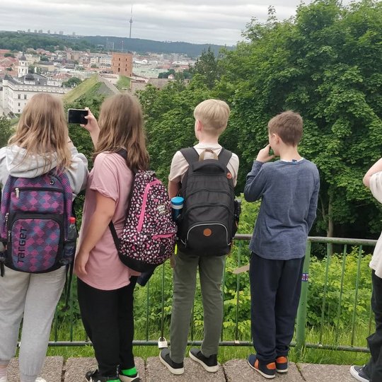 Moksleiviai mėgaujasi Vilniaus panorama nuo Trijų Kryžių kalno.