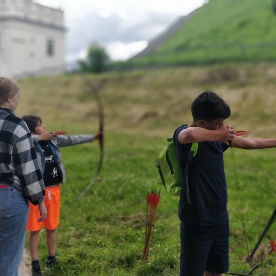Du berniukai į kažką taikydamiesi laiko įtempę lankus su strėlėmis.