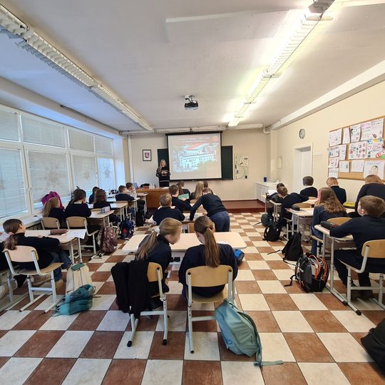 Mokiniai ruošiasi istorijos pamokai su edukatore.