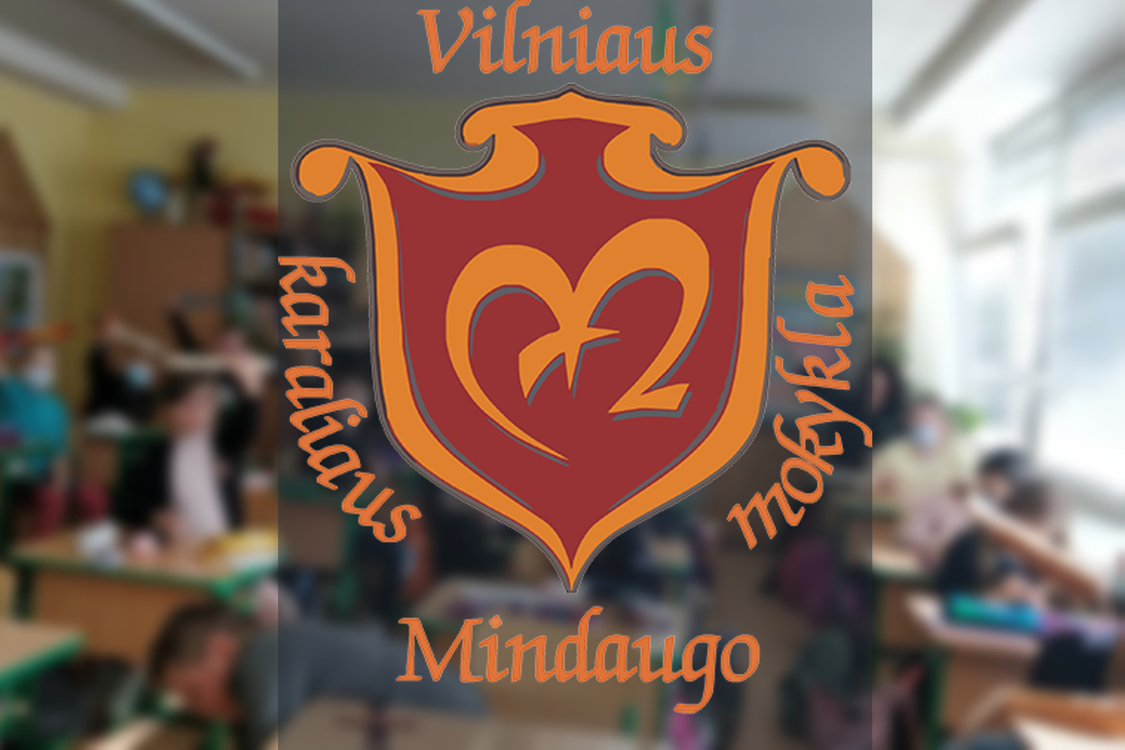 Mokiniai klasėje. Nuotraukos priekyje Vilniaus Karaliaus Mindaugo mokyklos logotipas.