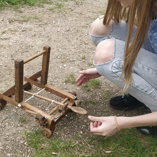 Mergaitė žaidžia su katapultos maketu.