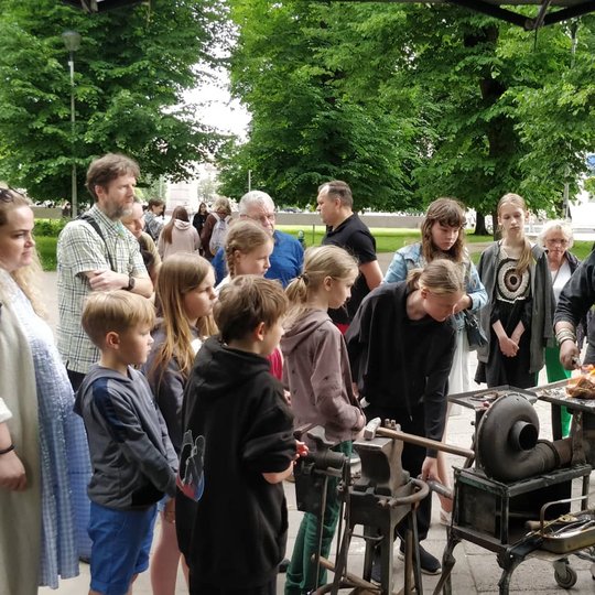 Kalvis Juozas Stankevičius susirinkusiems žmonėms rodo kaip gaminamas geležinis skeltuvas.