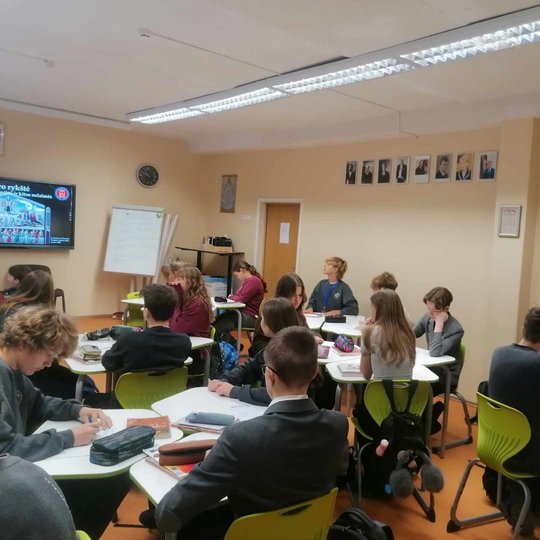 Mokiniai sėdi klasėje, edukatorė veda pamoką apie Buboninį marą.