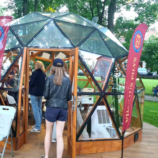 Į Vilniau pilių kupolą užeiną žmonės. Šalia įėjimo kėdė ant kurios kvietimas išmokti naudotis kompasu.  