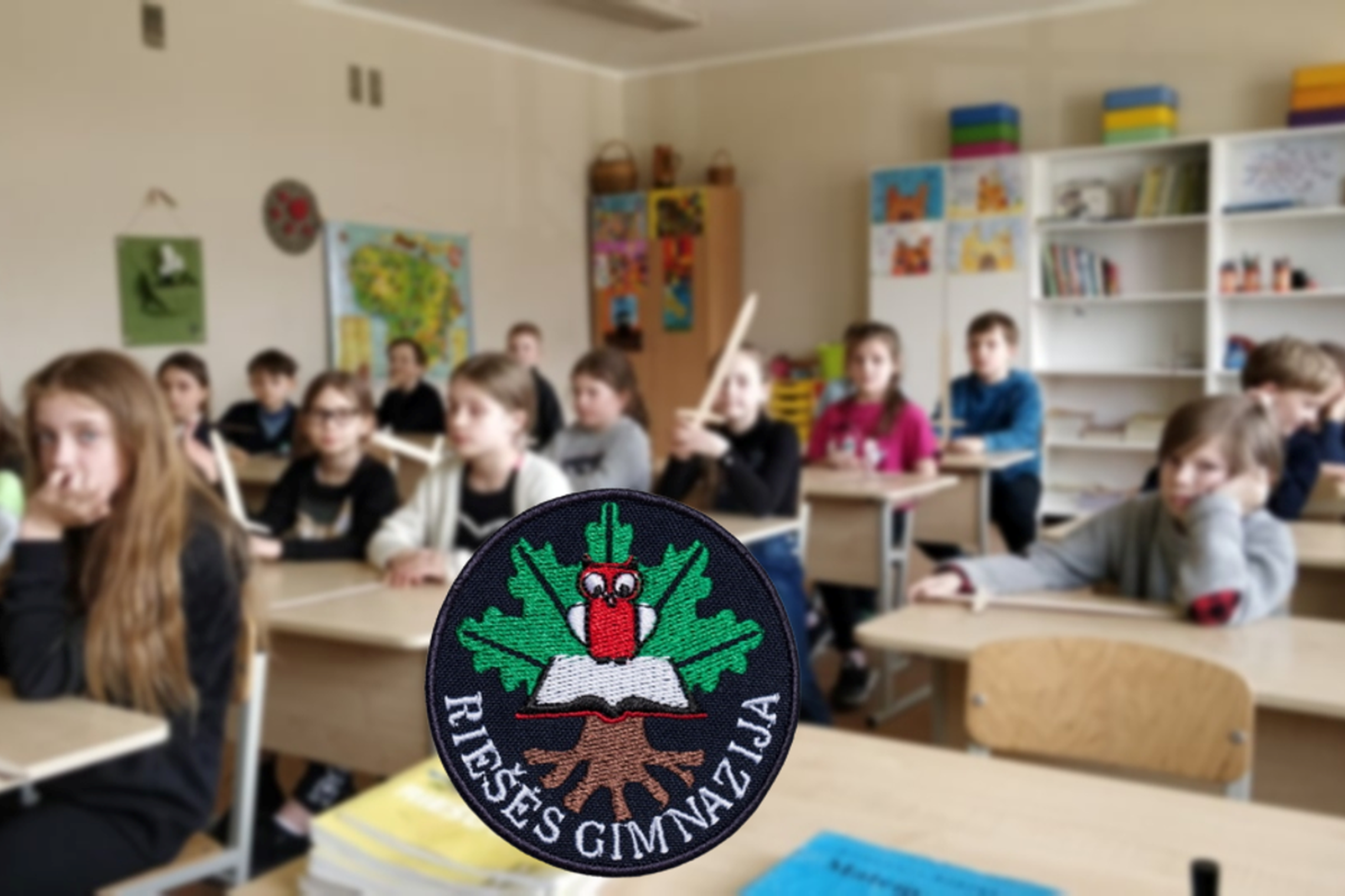 Mokiniai su mediniai kalavijais. Nuotraukos priekyje Riešės gimnazijos logotipas.