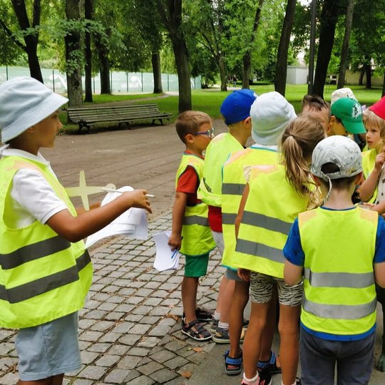 Vaikai su atšvaitinėmis liemenėmis pildo užduotis. 