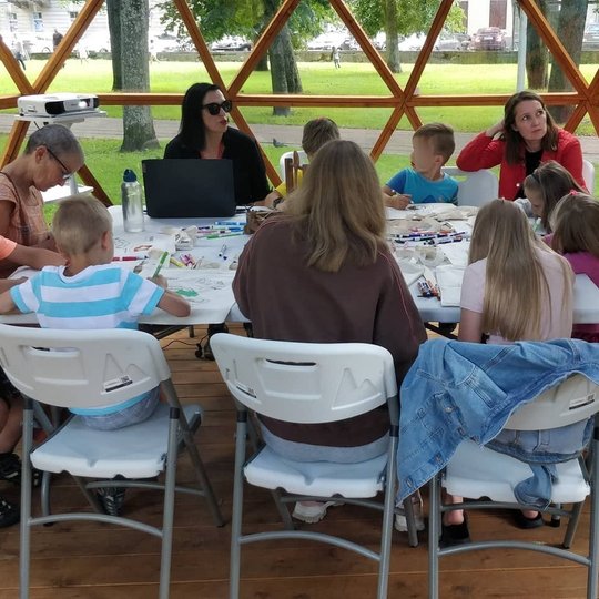 Edukatorė pasakoja apie Gediminą ir jo anūkus, o susirinkę vaikai ir mamos spalvina maišelius. 