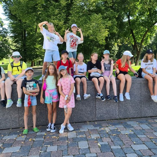 Sotvyklautojai pasiruošę ekskursijai, susėdę prie Pilių parko vartų.