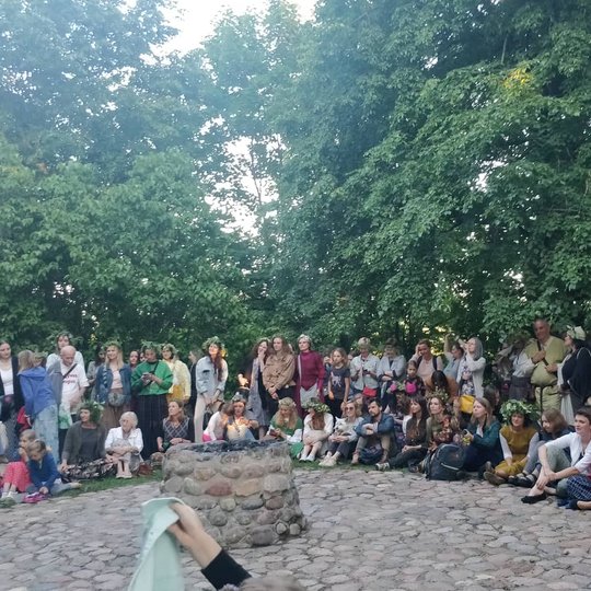 Žmonės susirinkę ratu aplink akmeninį aukurą.