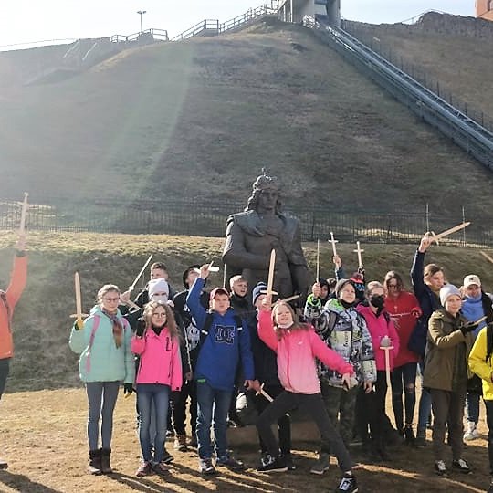 Jono Basanavičiaus penktokai, iškėlę medinius kalavijus virš galvų, šalia Vytauto statulos.
