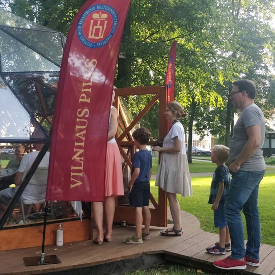 Žmonių kupinas Vilniaus pilių kupolas. Šalia kupolo žmonės smalsiai domisi kas jame vyksta.