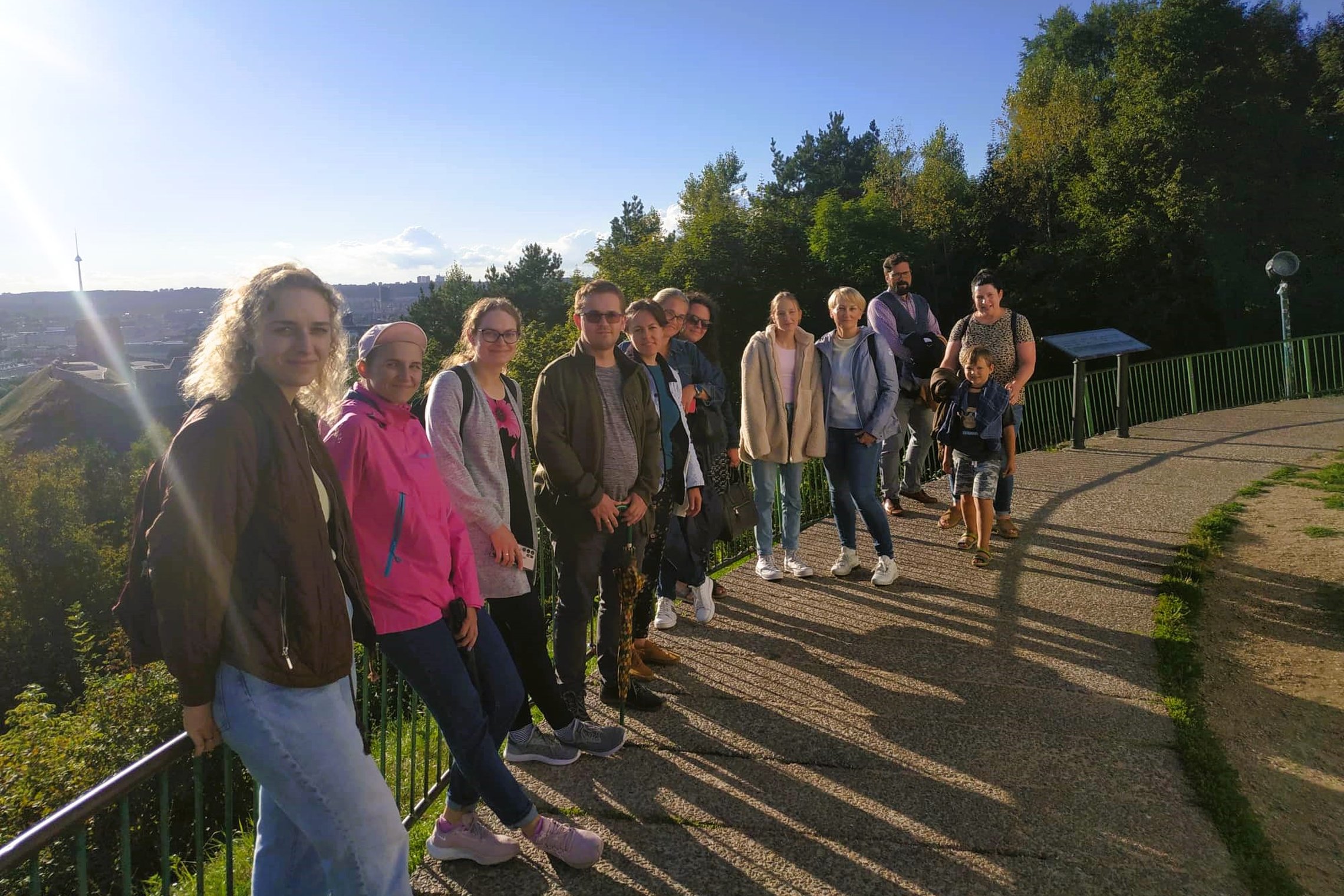Ekskursijos dalyviai pozuoja nuotraukai priešais Trijų Kryžių paminklą. Nuotrauka daryta šonu.  