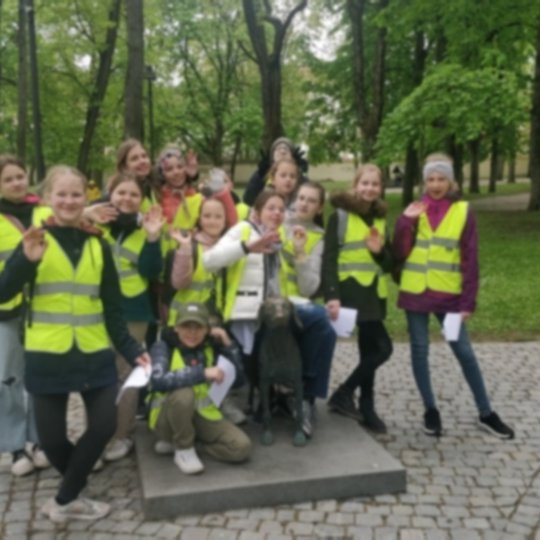 Mokiniai su mokytoja pozuoja nuotraukai šalia lietuviškų skalikų.