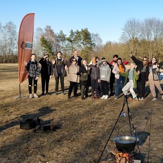 Jaunieji turistai ant Stalo kalno pozuoja nuotraukai. Priešais juos, katilas ant laužo.
