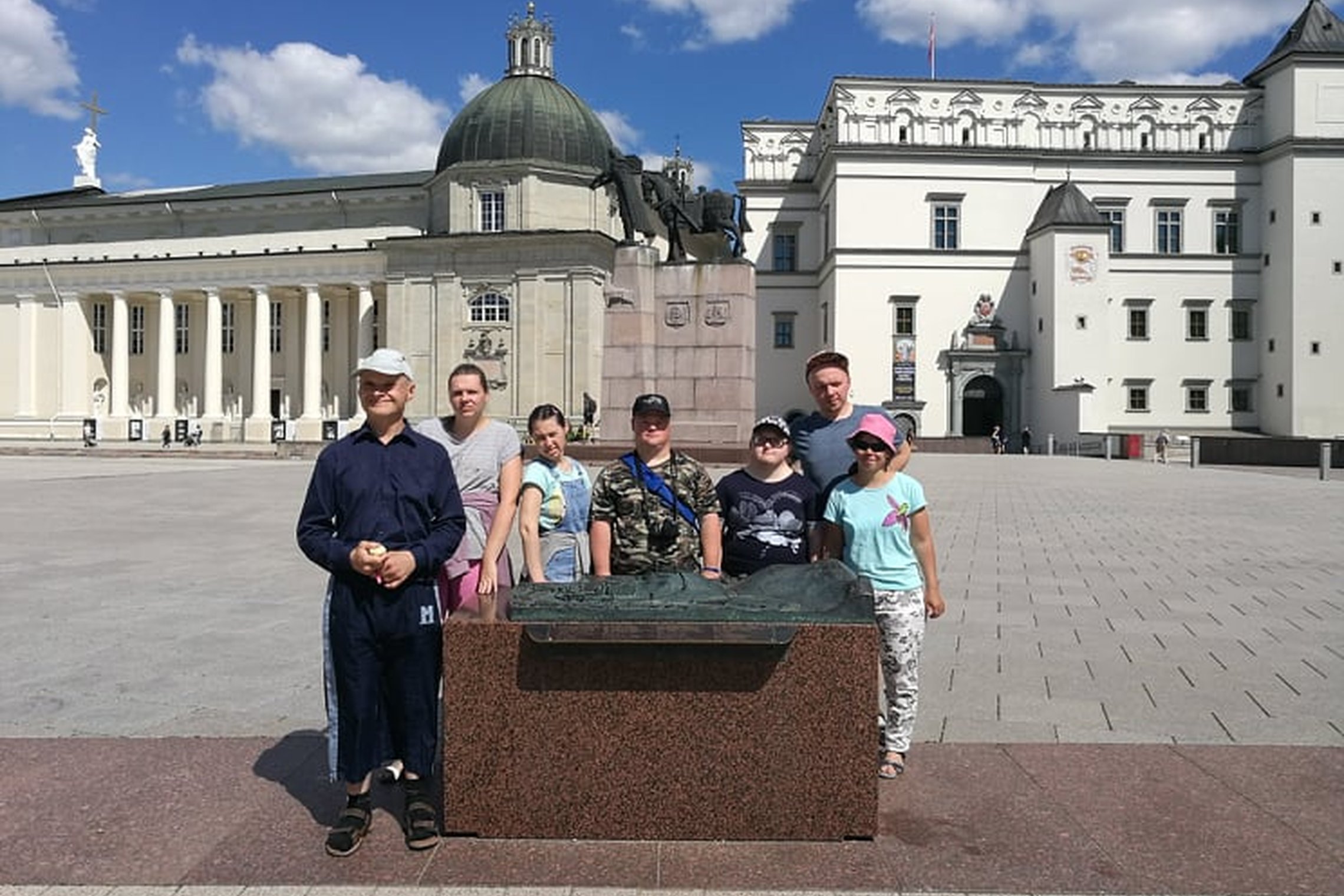 Ekskursijos dalyviai sustoje pozuoja šalia Vilniaus pilių teritorijos maketo. Fone matosi kunigaikščio Gėdinimo paminklas, Valdovų rūmai ir Katedra.