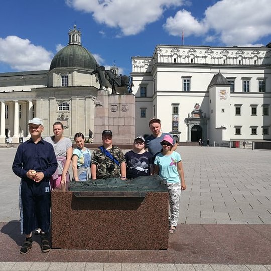 Ekskursijos dalyviai sustoje pozuoja šalia Vilniaus pilių teritorijos maketo. Fone matosi kunigaikščio Gėdinimo paminklas, Valdovų rūmai ir Katedra.