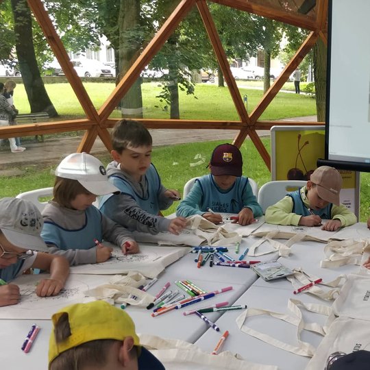 Vilniaus pilių kupole vaikai prie stalo spalvina valdovų atvaizdus, esančius ant medžiaginių maišelių.