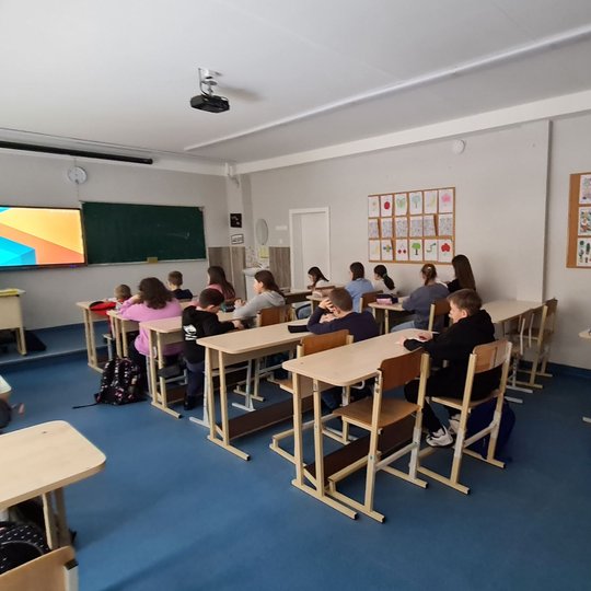 Klasė mokinių, fotografuota jiems iš nugaros. 
