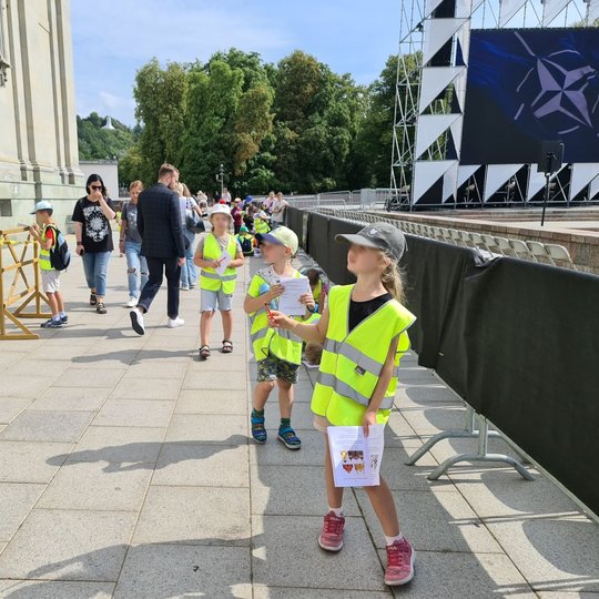 Vaikai apžiūrinėja Arkikatedrą besiklausydami orkestro muzikos.