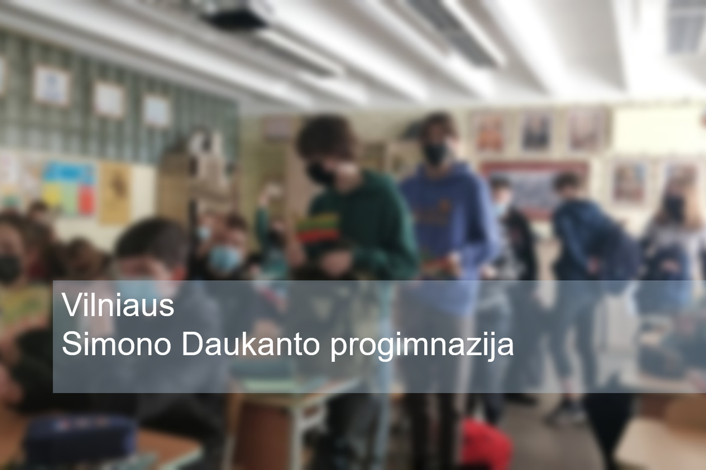 Mokiniai klasėje. Nuotraukos priekyje parašyta "Vilniaus Simono Daukanto progimnazijos".