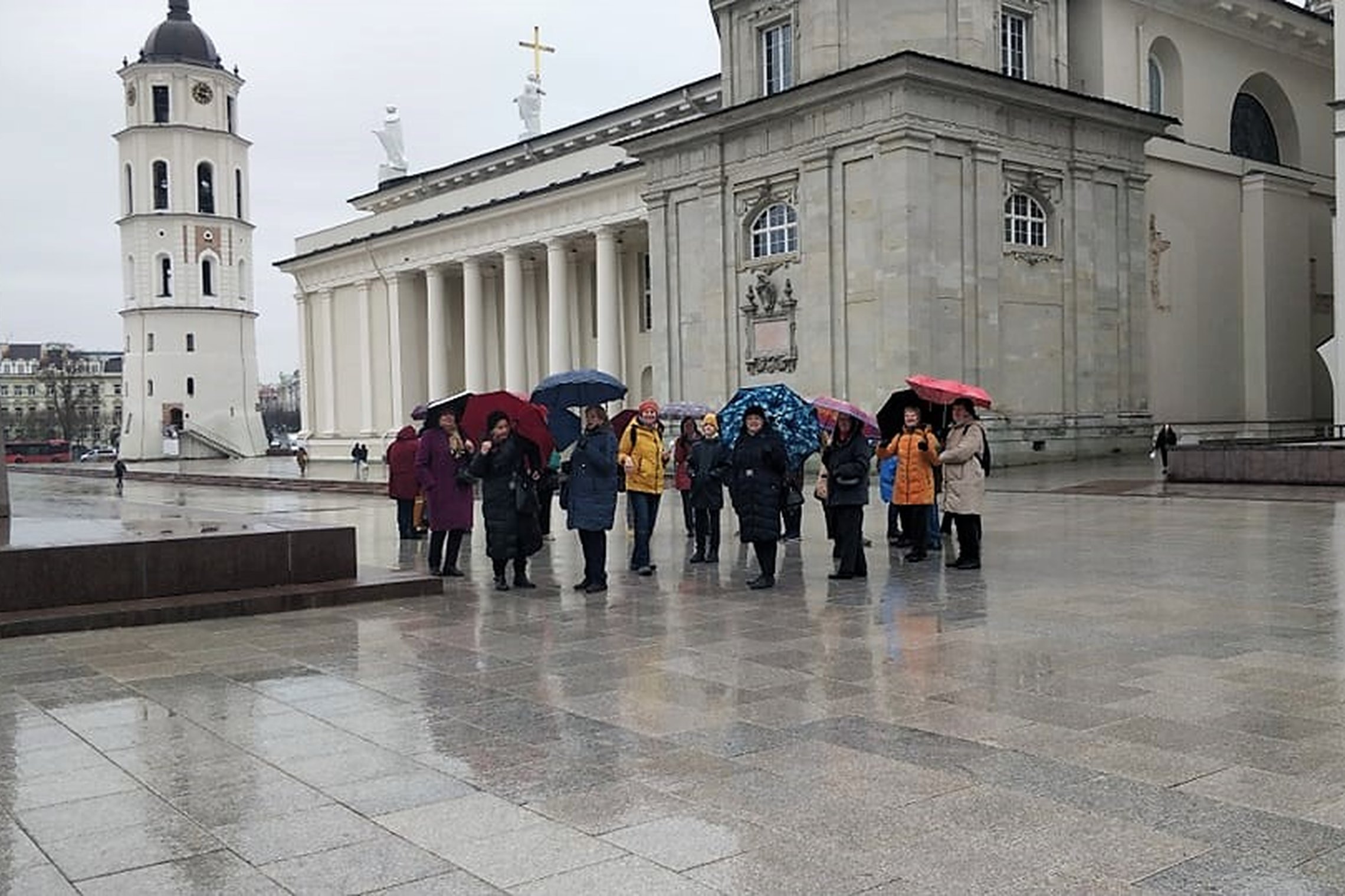 Ekskursijos dalyviai lietingą diena, šalia Gedimino paminklo.