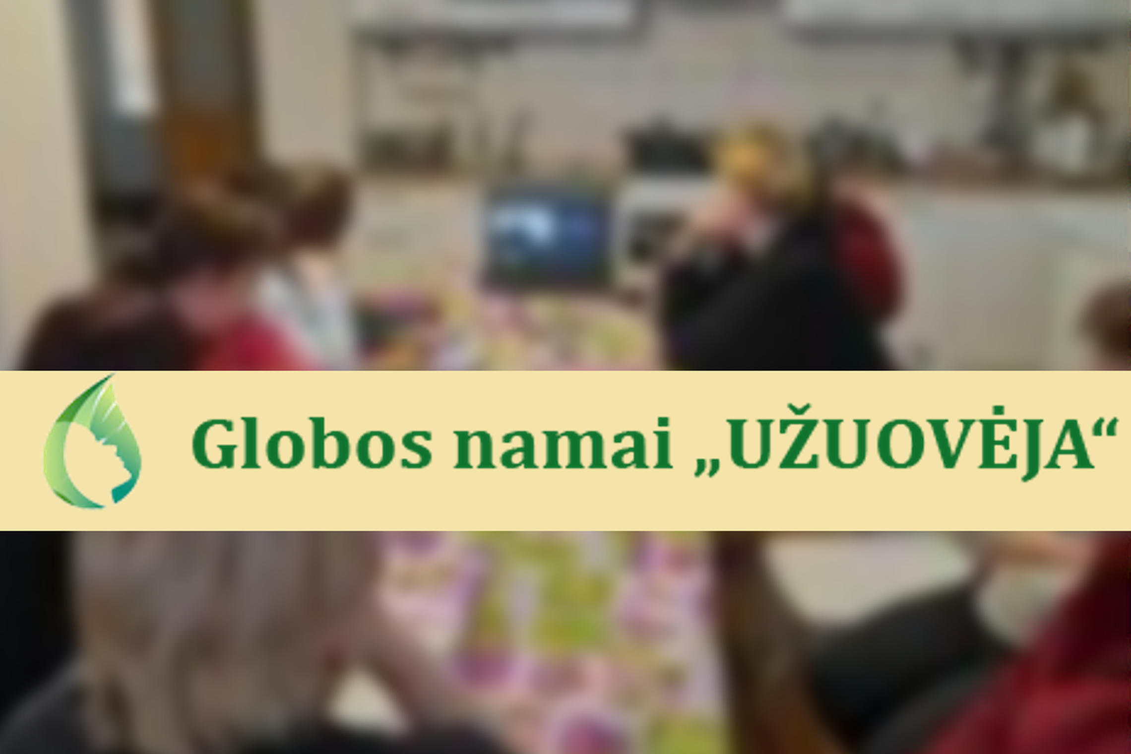 Nuotraukoje matosi globos namų „Užuovėja“ lankytojai prie stalo. Nuotraukos priekyje Globos namų „Užuovėja“ pavadinimas ir logotipas.