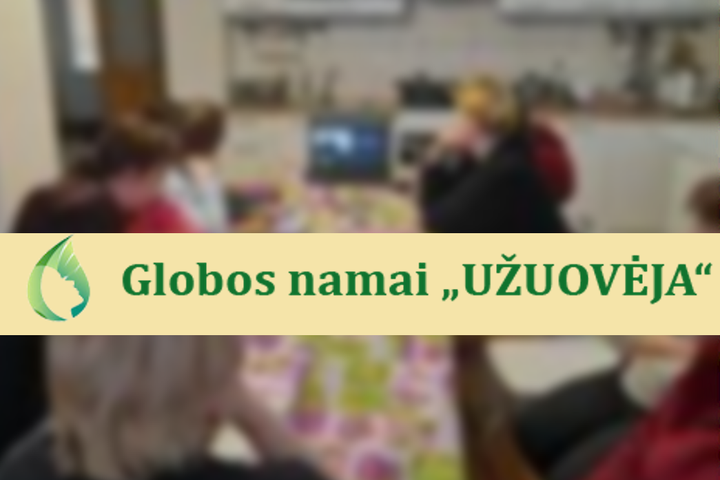 Nuotraukoje matosi globos namų „Užuovėja“ lankytojai prie stalo. Nuotraukos priekyje Globos namų „Užuovėja“ pavadinimas ir logotipas.