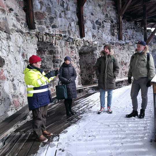 Kolega iš Suomijos įnirtingai pasakoja rezervato darbuotojams apie Suomijos pilis, vienoje iš Suomijos pilių.