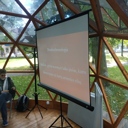 Projektoriaus ekranas, kuriame rodoma skaidrė su edukacijos pavadinimu Vilniaus pilių kupole.