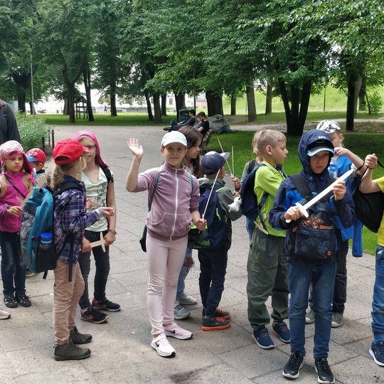 Vaikai su mediniai kalavijais šalia Vilniaus pilių kupolo.