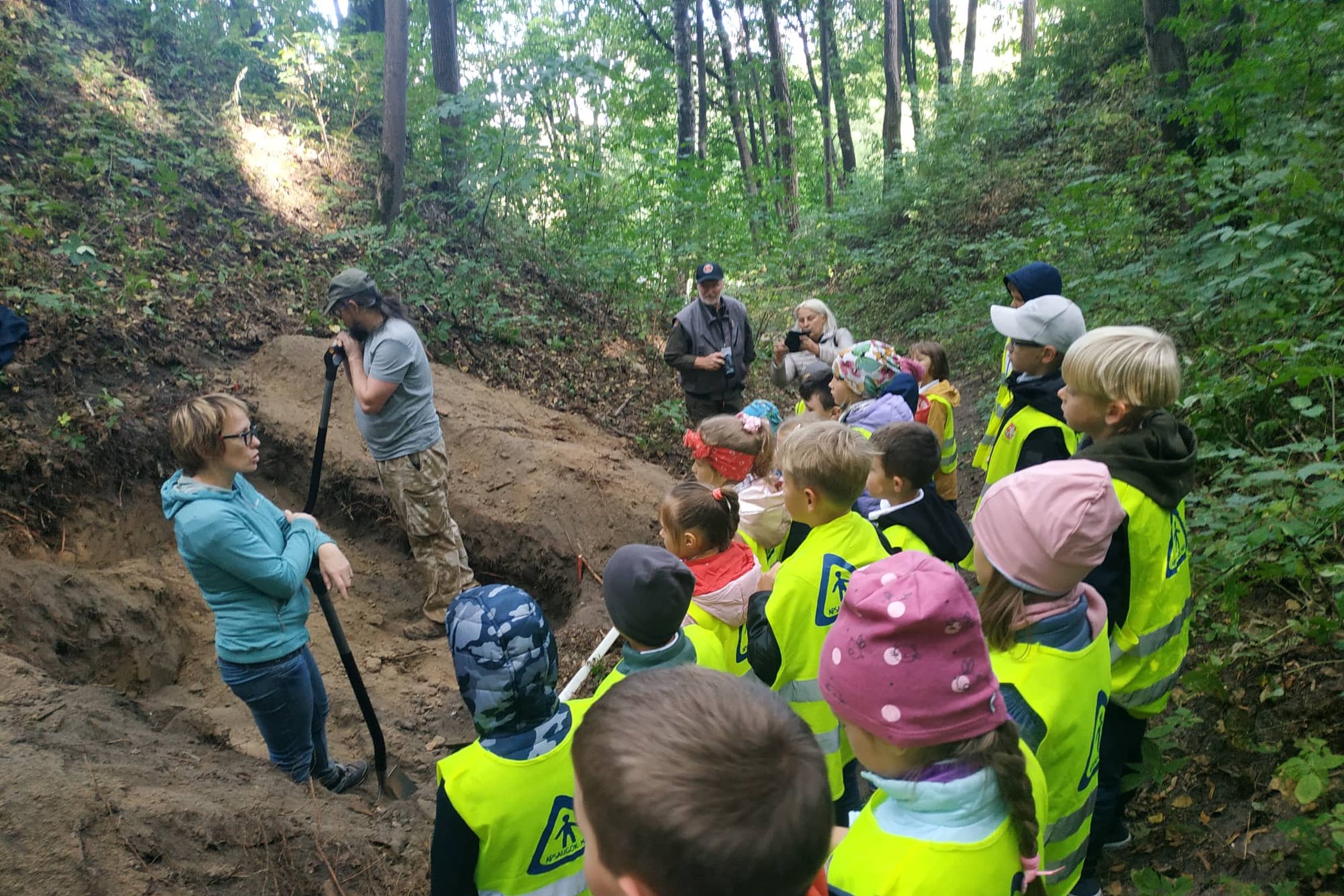 Besidarbuojantis archeologai pasakoja mokiniams Kreivosios pilies istoriją.