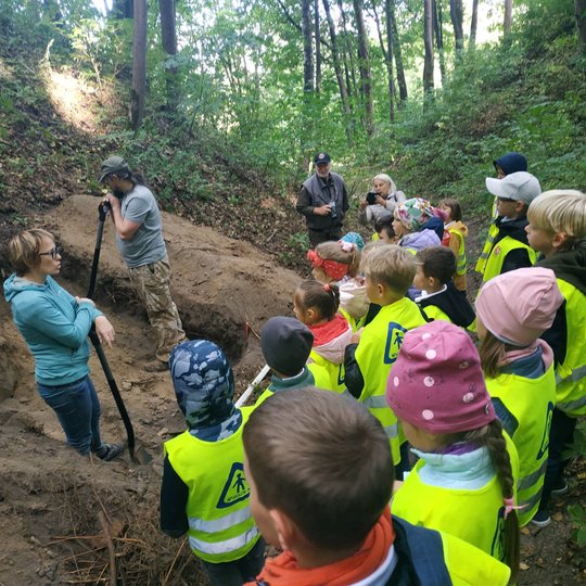 Besidarbuojantis archeologai pasakoja mokiniams Kreivosios pilies istoriją.